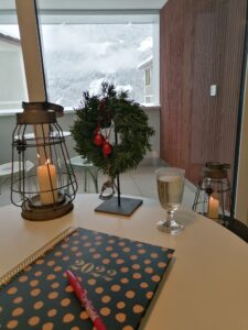 Tisch mit Laternenkerze, Weihnachtskranz und 2022 Notizbuch Blick in die Schneelandschaft